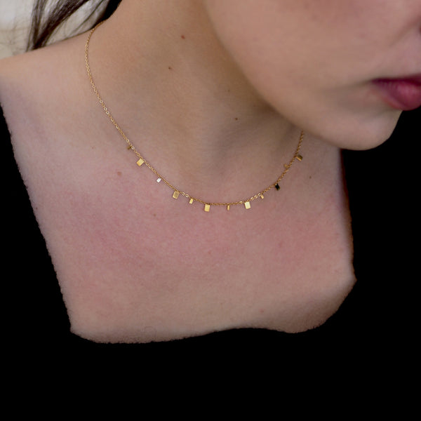 Close up photo of a woman with Golden squares necklace